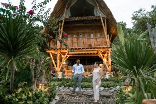a couple standing in front of a tree house at Penida Bambu Green Suites in Nusa Penida