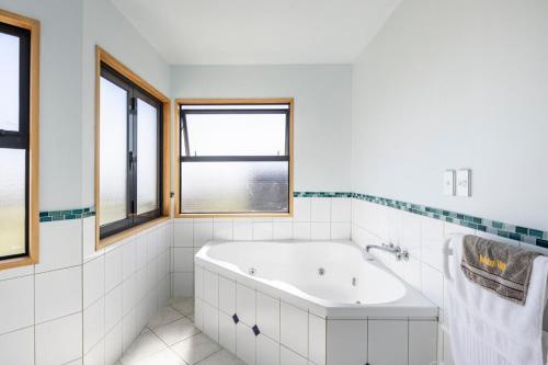 a white bathroom with a tub and windows at Spacious modern executive home in Wellington