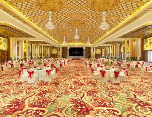 a large banquet hall with white tables and red chairs at Regal Palace Hotel in Dongguan