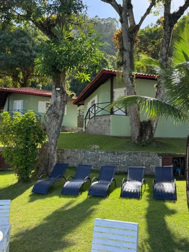 a group of chairs sitting on the grass in front of a house at Pousada Gipoia in Angra dos Reis