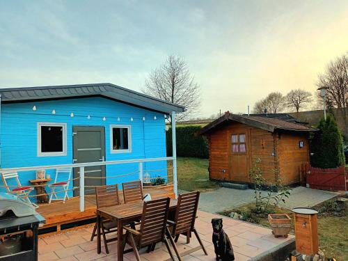 a blue tiny house with a table and chairs at Bussardhorst in Ruppichteroth