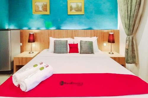 een slaapkamer met een groot wit bed met een rode deken bij RedDoorz near Focal Point Medan in Sunggal