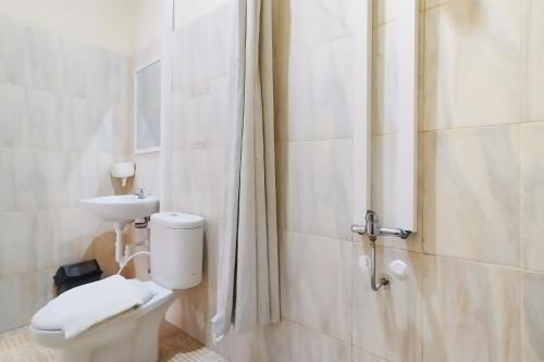 een witte badkamer met een toilet en een wastafel bij RedDoorz near Focal Point Medan in Sunggal