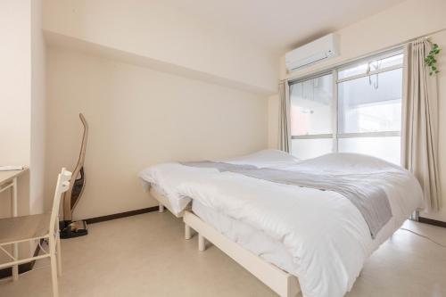a white bedroom with a bed and a window at Minami-Fukuoka Good Place House in Fukuoka
