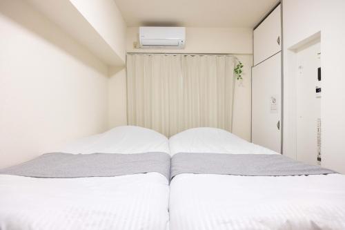 a bedroom with a bed with white sheets at Minami-Fukuoka Good Place House in Fukuoka