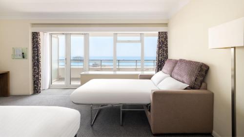 a room with a couch and a chair and a window at Holiday Inn Brighton Seafront by IHG in Brighton & Hove