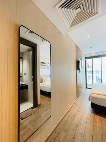 a mirror in a room with a bed and a bathroom at Apec Mandala Phú Yên - Luxury Codotel in Phước Hậu