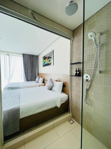 a bedroom with a bed and a glass shower at Apec Mandala Phú Yên - Luxury Codotel in Phước Hậu