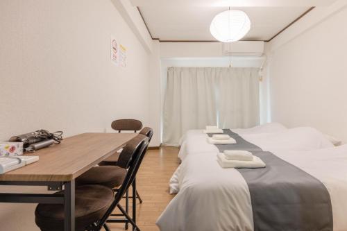 筑紫野市Murasaki Good Place House的有两张床、一张桌子和几把椅子的房间