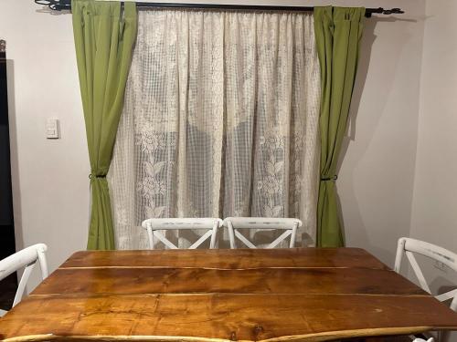 een houten tafel en stoelen voor een gordijn bij Casa cómoda y acogedora en San Pedro de Atacama in San Pedro de Atacama