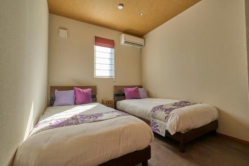two beds in a small room with a window at VILLA SENSE kujukuri in Kujukuri