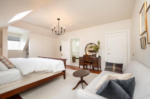 a white bedroom with a bed and a couch at No. 5 East in Winnipeg