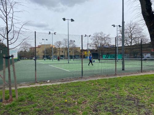 a group of people playing tennis on a tennis court at Harolds Home in London