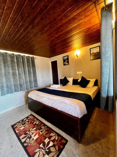 a bedroom with a large bed with a wooden ceiling at EcoEscape Mukteshwar in Mukteswar