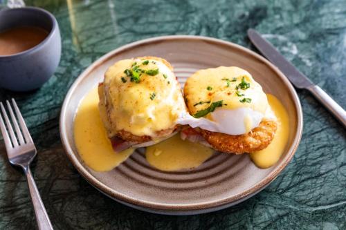 a plate of food with two fried eggs and sauce at Kimpton - The Forum Hotel by IHG in Charlottesville