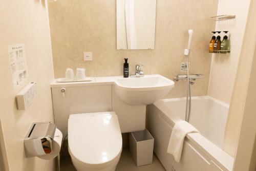 a bathroom with a toilet and a sink and a bath tub at Ryokan Asakusa Shigetsu in Tokyo
