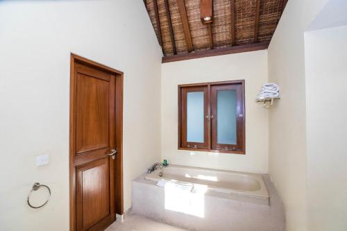a bathroom with a tub and a wooden door at Villa Diana Bali in Legian