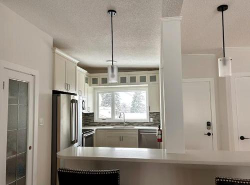 a kitchen with white cabinets and a counter top at Modern 3BR Near Airport & DT in Calgary