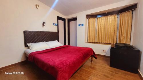 a bedroom with a bed with a red blanket at Green Woods Homestay in Kodaikānāl