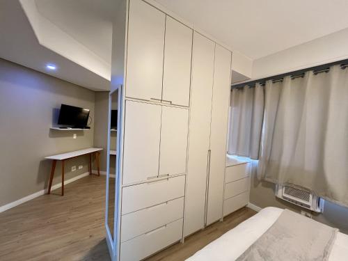 a bedroom with white cabinets and a bed and a television at Hotel Bienal Ibirapuera Un409 in Sao Paulo