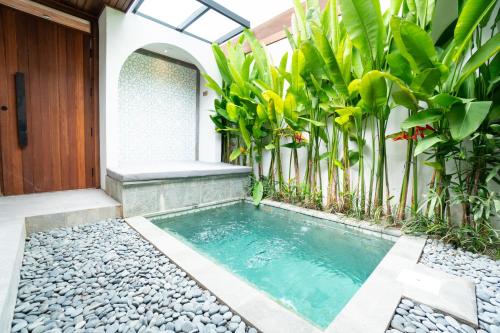 a swimming pool in front of a house with plants at Blue Calm Villas Bali in Tumbak Bayuh