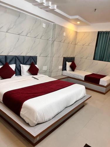 a bedroom with two beds with red and white pillows at Hotel the grand pritam in Gandhinagar