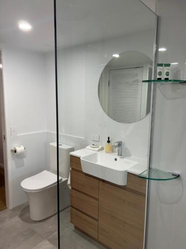 a bathroom with a sink and a toilet and a mirror at Apartment 12 On Trinity Beach in Trinity Beach