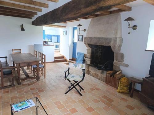 un salon avec une cheminée en pierre et une table dans l'établissement Maison en pierre pour 6 personnes à 400m de la plage, Secteur Logeo - FR-1-639-139, à Sarzeau
