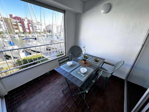 une table et des chaises dans une pièce avec une grande fenêtre dans l'établissement Studio Cabine Calme, Vue Canal, Près Commerces - FR-1-702-71, au Cap d'Agde