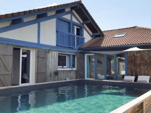 une maison avec une piscine devant une maison dans l'établissement Maison Landaise pour 12 personnes proche océan, piscine, WIFI inclus - FR-1-50-165, à Bias