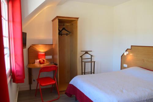 a bedroom with a bed and a table with a red chair at L'annexe in Le M&ecirc;le-sur-Sarthe