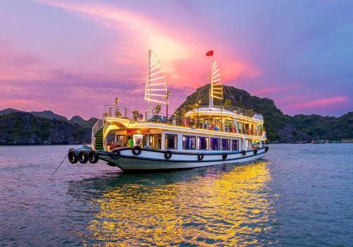 a boat on the water with a sunset in the background at Private Balcony Hotel in Cat Ba