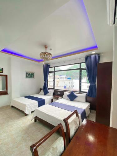 a hotel room with two beds and a table and chairs at Private Balcony Hotel in Cat Ba