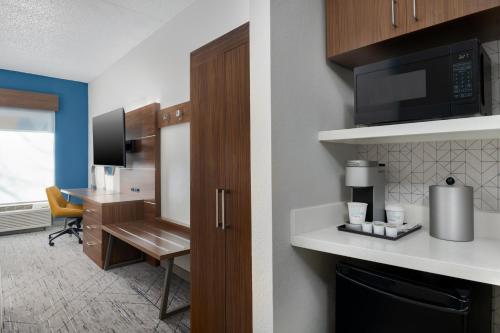 a room with a kitchen with a desk and a microwave at Holiday Inn Express Hotel & Suites Bentonville by IHG in Bentonville