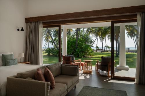 a living room with a couch and a large sliding glass door at Kalkudah Beach House in Batticaloa