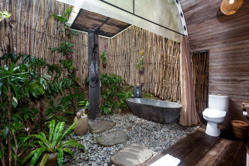 a bathroom with a bath tub and a toilet at Sacred Beji by GenuineHost in Payangan