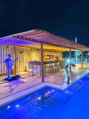 two people standing next to a swimming pool at night at Bali Mar Hotel in Natal