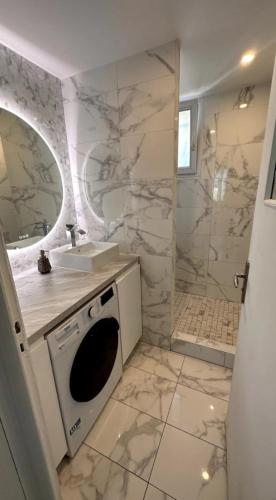 une salle de bain avec un lavabo et une machine à laver dans l'établissement Cosy appartement 3 chambres & parking privé, à Lyon