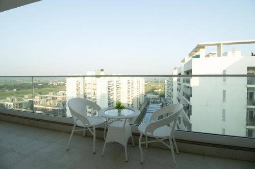 グルガオンにあるPosh 1BR Apartment In Gurugram With Club Facilitiesの眺めの良いバルコニーにテーブルと椅子が置かれている