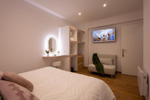 a white bedroom with a bed and a chair at T2 center parking air conditioning Wi-Fi in Avignon
