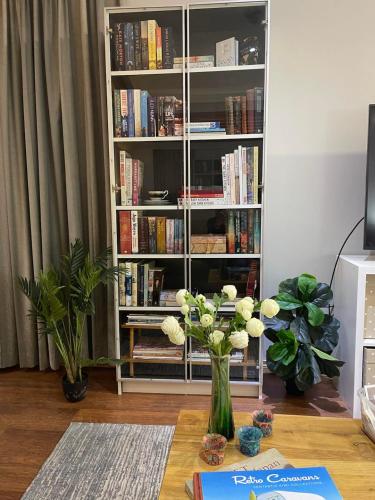 a book shelf with a vase of flowers on a table at AC 1 Bed Studio Apartment 25+ Non Smokers in Warnbro
