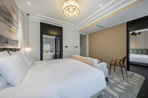 a bedroom with a large white bed and a chair at CHONGQING MANQUE MANSION in Chongqing