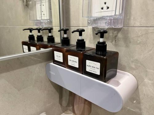 une rangée de distributeurs de savon sur un mur dans une salle de bains dans l'établissement Sunny Deluxe Apartment 1-bedroom And 1-living Room, à Gia Lâm Pho