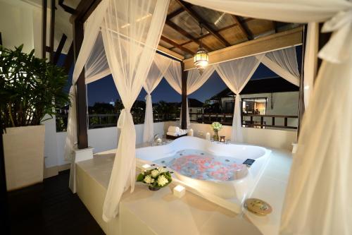 a bath tub in a room with a window at Rarin Jinda Wellness Spa Resort in Chiang Mai