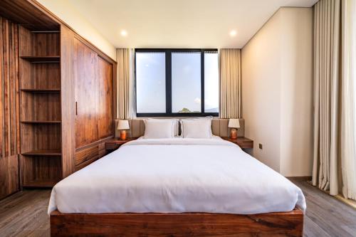 a bedroom with a large white bed and a window at Cami Riverside Resort Da Nang in Da Nang