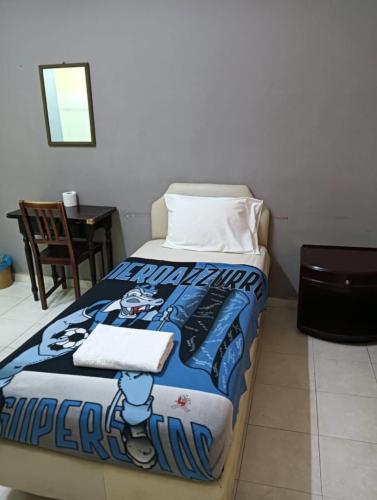 a bedroom with a bed with a football blanket at Kota Lodge Guest House in Melaka