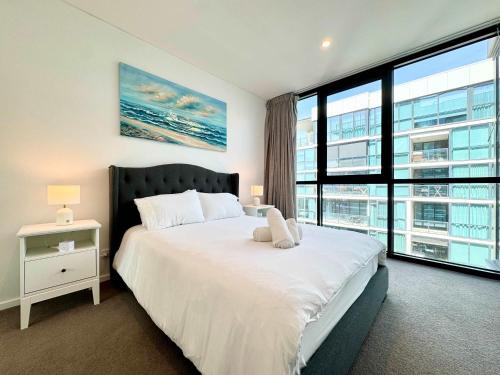 Un dormitorio con una cama grande y una ventana grande. en Luxury CBD Escape - 1BR Apartment with Pool & Gym, en Adelaida