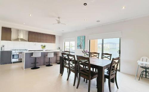 a kitchen and dining room with a table and chairs at StayAU 5BR Idyllic Lakefront Escape Point Cook in Point Cook