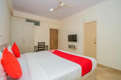 a bedroom with a bed with red pillows and a tv at The Pride Hill-tone in Bangalore