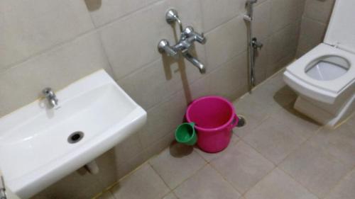 a bathroom with a sink and a toilet and a bucket at The Pride Hill-tone in Bangalore